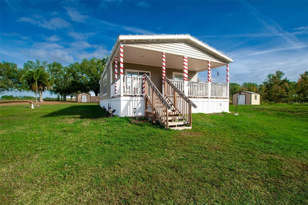 A single-story manufactured home features a covered front porch with candy-cane striped support columns — 2837 NE PERSIMMON DRIVE, ARCADIA, FL