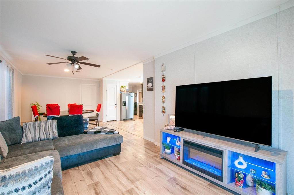 A living room features a large television on a lighted fireplace console and a dining area — 2837 NE PERSIMMON DRIVE, ARCADIA, FL
