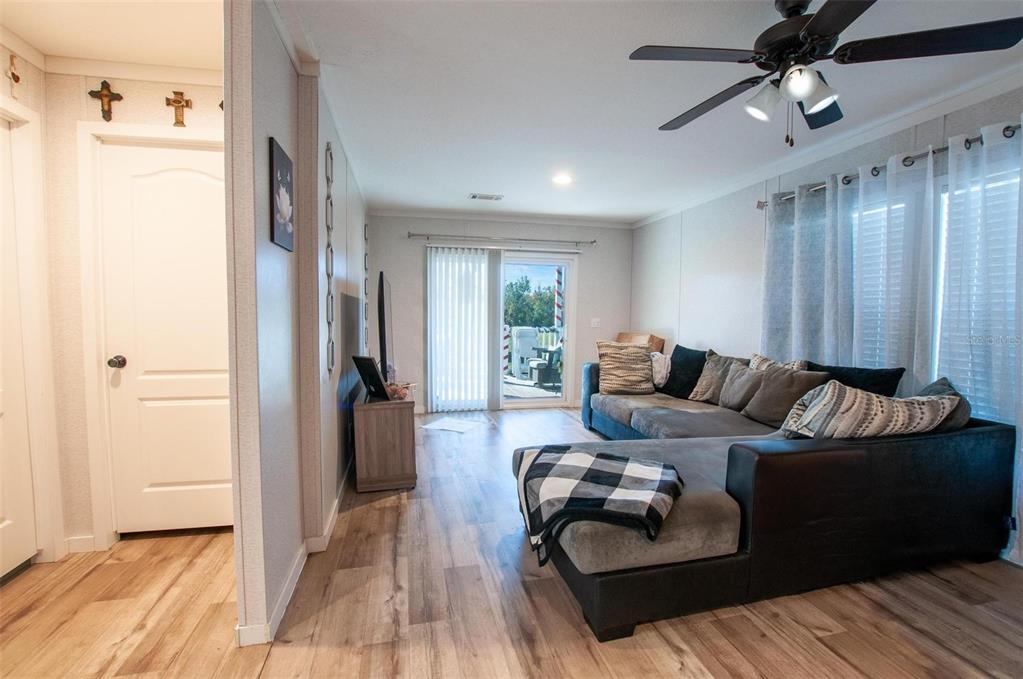 A living room features wood-look flooring, a gray sectional sofa, and a sliding glass door — 2837 NE PERSIMMON DRIVE, ARCADIA, FL