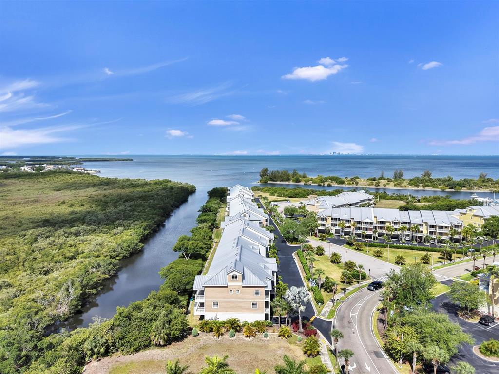 An aerial view shows a multi-story residential building situated between a waterway and mangroves — 3202 MANGROVE POINT DRIVE, RUSKIN, FL