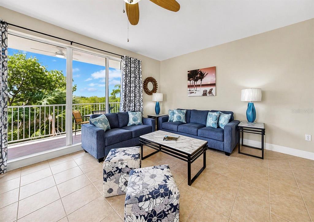 A living room features blue sofas, floral ottomans, a marble coffee table, and a balcony view — 3202 MANGROVE POINT DRIVE, RUSKIN, FL