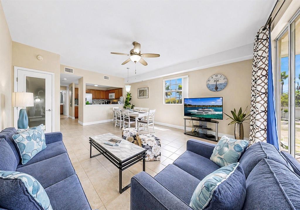 A living room with blue sofas, a dining area, and a kitchen in the background — 3202 MANGROVE POINT DRIVE, RUSKIN, FL