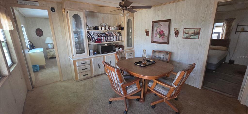 A dining area features wood-paneled walls, a round table with four chairs, and built-in shelving — 16806 HARLEY STREET, HUDSON, FL