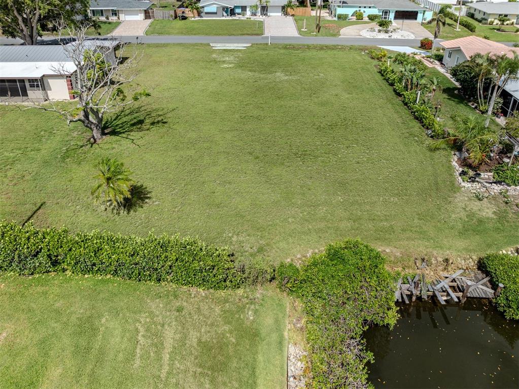An aerial view shows a vacant, grassy residential lot bordering a small canal — 458 N SHORE DRIVE, OSPREY, FL