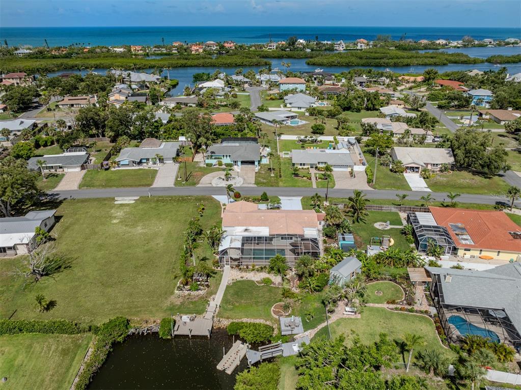 An aerial view shows a waterfront house with a pool cage, dock, and large yard — 458 N SHORE DRIVE, OSPREY, FL