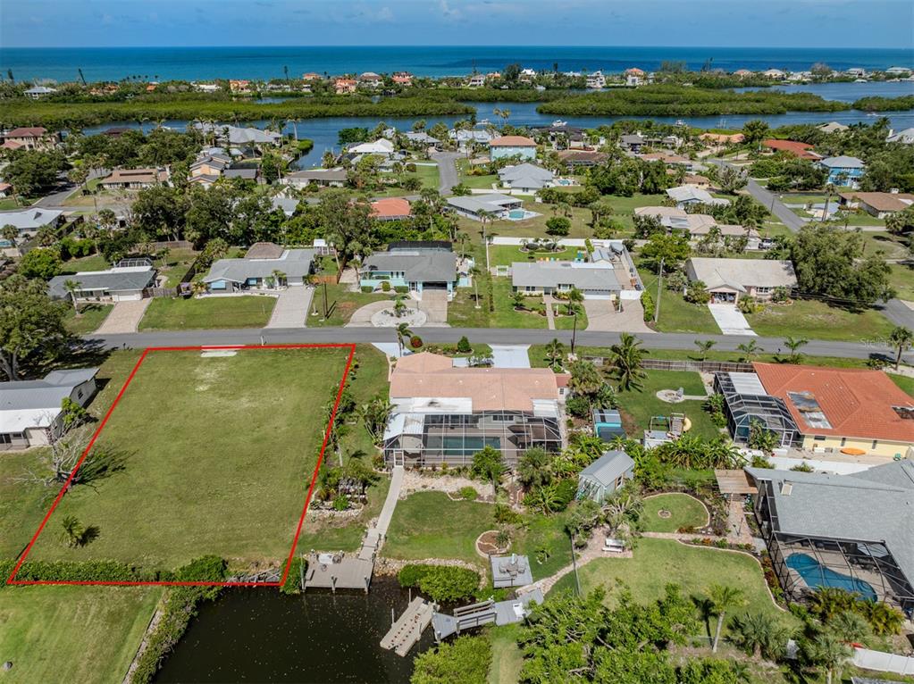 An aerial view shows a vacant waterfront lot outlined in red next to a house — 458 N SHORE DRIVE, OSPREY, FL