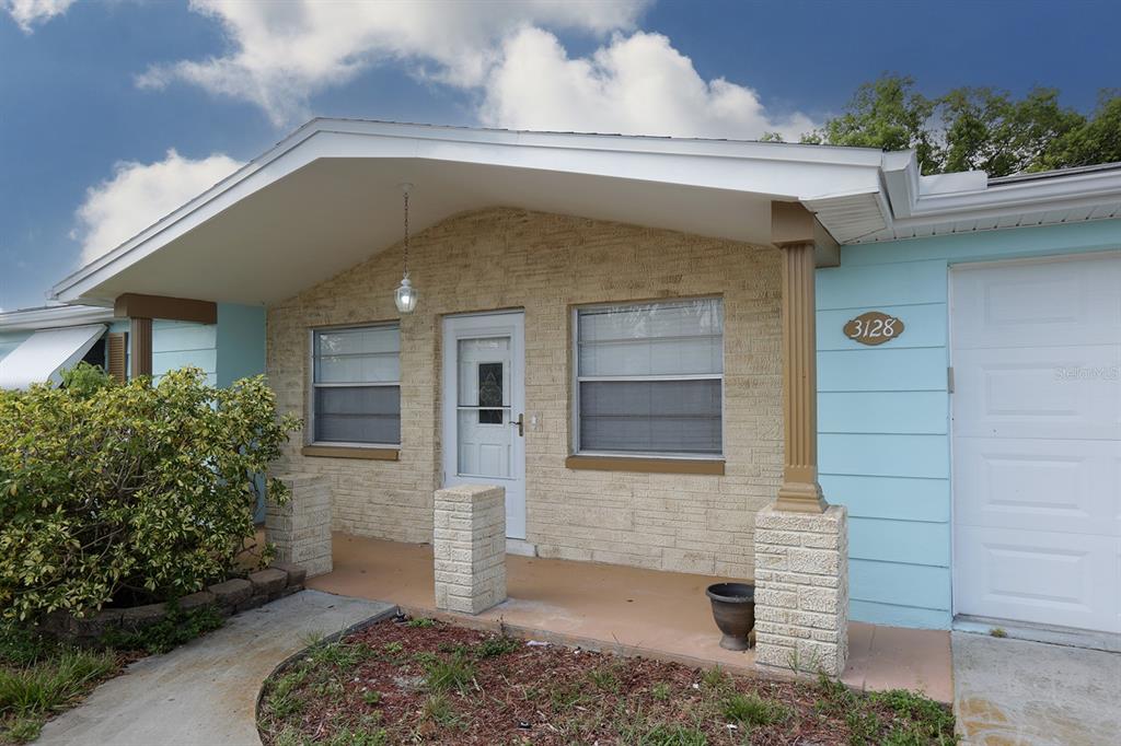 A bedroom with light blue walls, a queen bed, mirrored closets, and wood-look flooring — 3128 KILBURN ROAD, HOLIDAY, FL