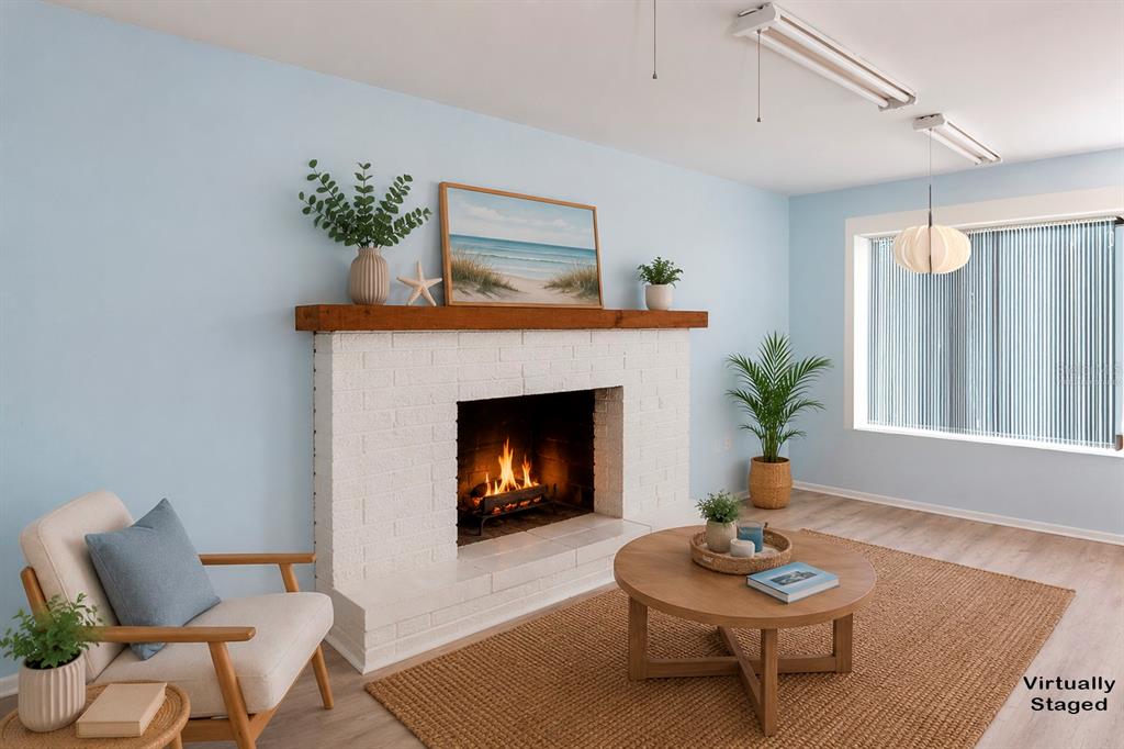 A room with light blue walls, wood-look flooring, and a white brick fireplace with a mantel — 3128 KILBURN ROAD, HOLIDAY, FL