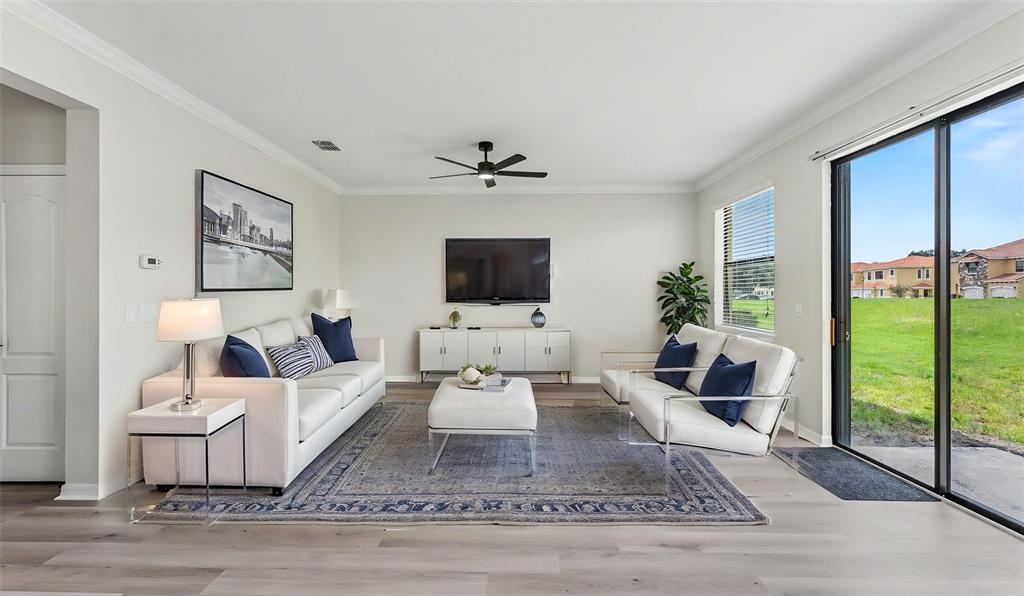 A living room features white furniture, a blue patterned rug, and a sliding glass door — 1126 CHERVIL DR, POINCIANA, FL