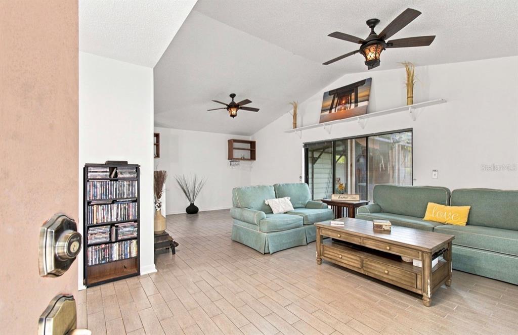 A living room features light tile floors, two teal sofas, and a wooden coffee table — 1932 GREGORY DRIVE, TAMPA, FL