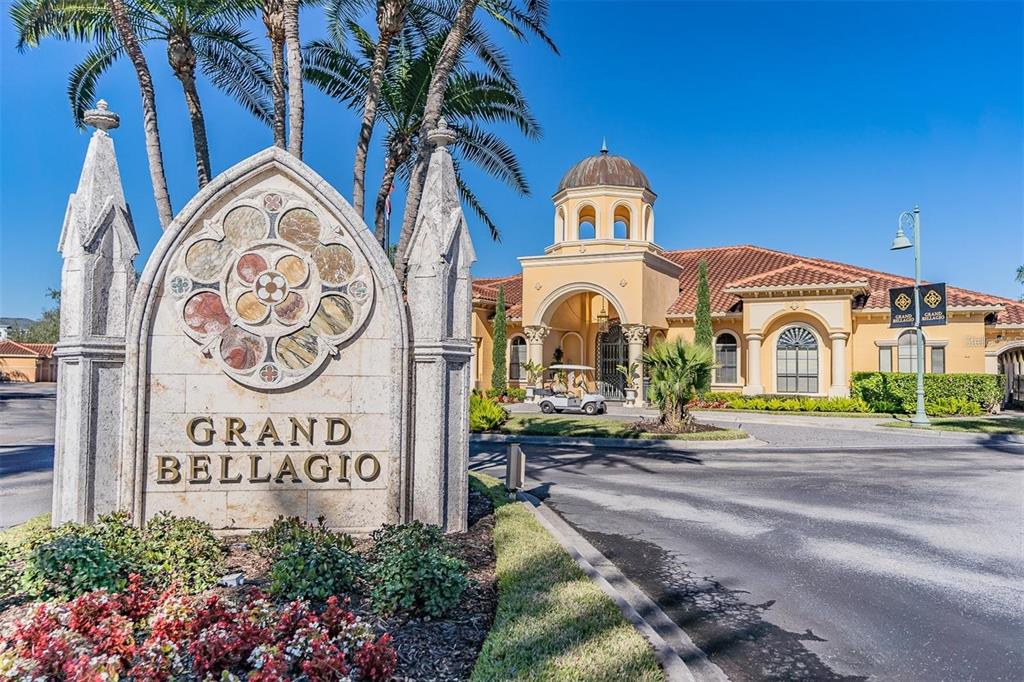 A stone monument with the name Grand Bellagio stands before a Mediterranean-style clubhouse with palm trees — 2773 VIA CIPRIANI UNIT 1330B, CLEARWATER, FL