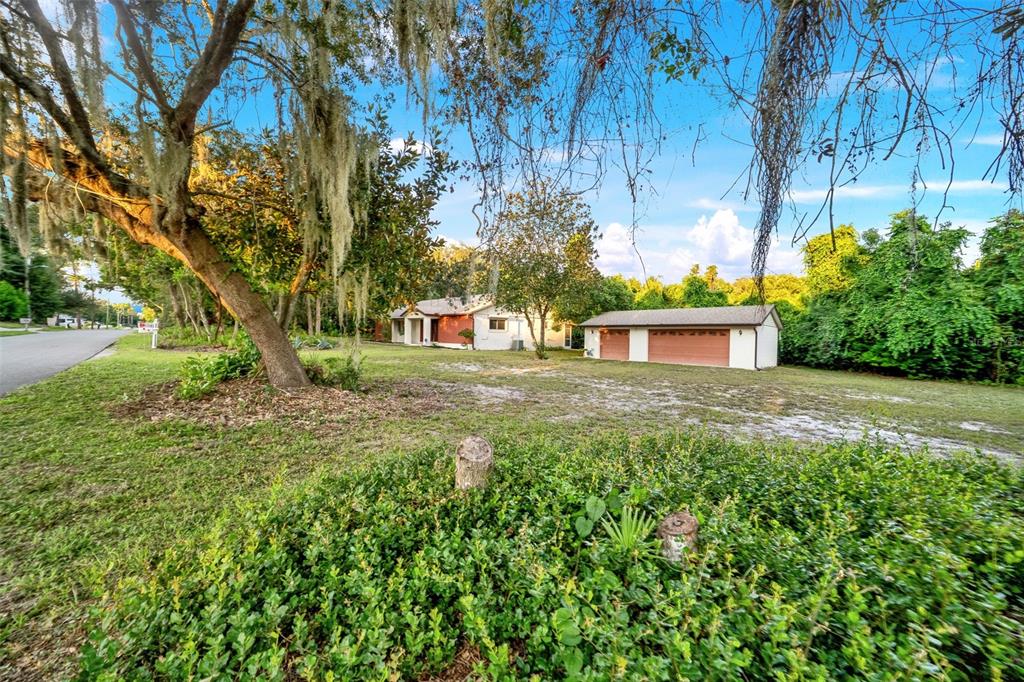 A single-story house with a detached two-car garage sits on a large, grassy lot — 245 AGUA VISTA STREET, DEBARY, FL