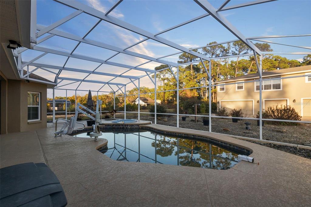 A single-story house with a beige exterior, arched windows, and a large concrete driveway at sunset — 73 SANCTUARY AVENUE, DEBARY, FL
