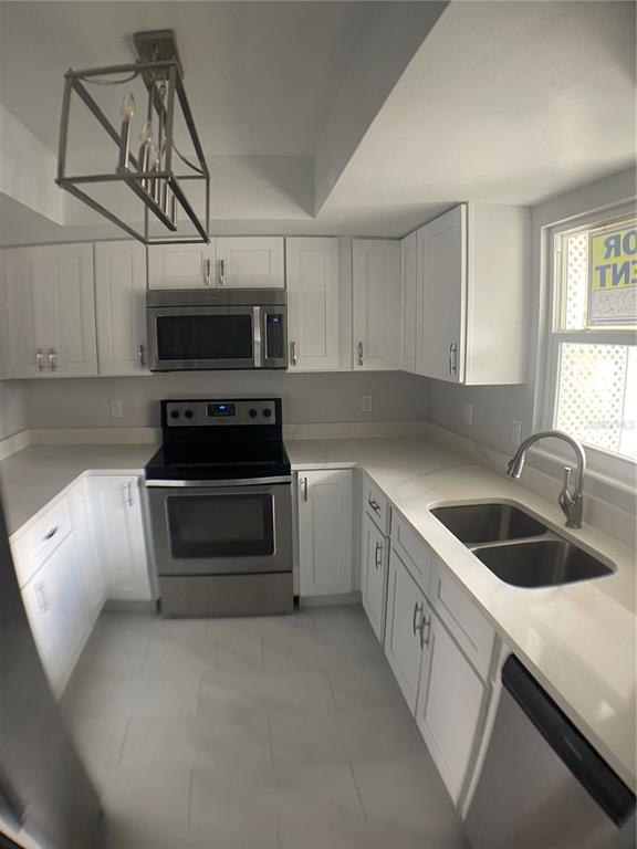 A kitchen with white cabinets, stainless steel appliances, and light countertops — 152 DOUGLAS ROAD W UNIT B, OLDSMAR, FL