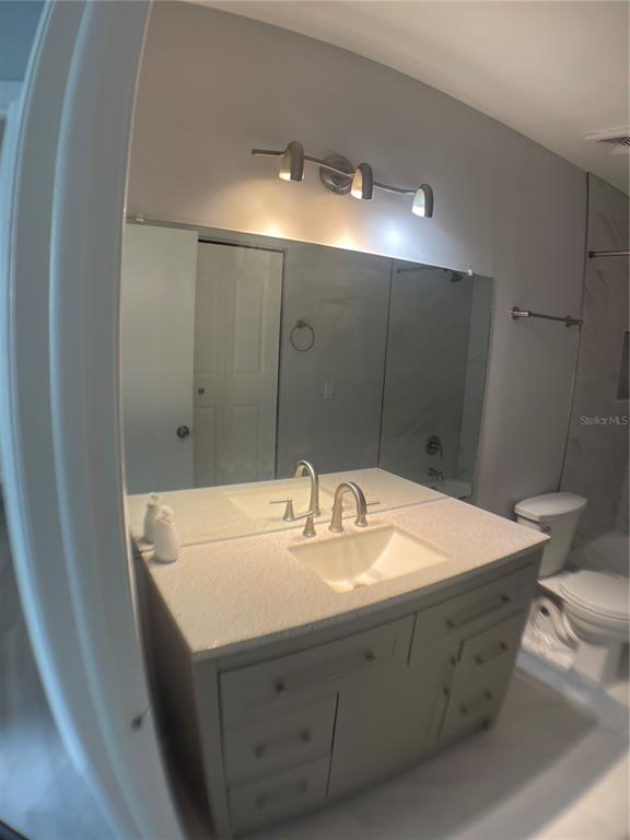 A bathroom features a gray vanity with a light countertop, a sink, and a mirror — 152 DOUGLAS ROAD W UNIT B, OLDSMAR, FL