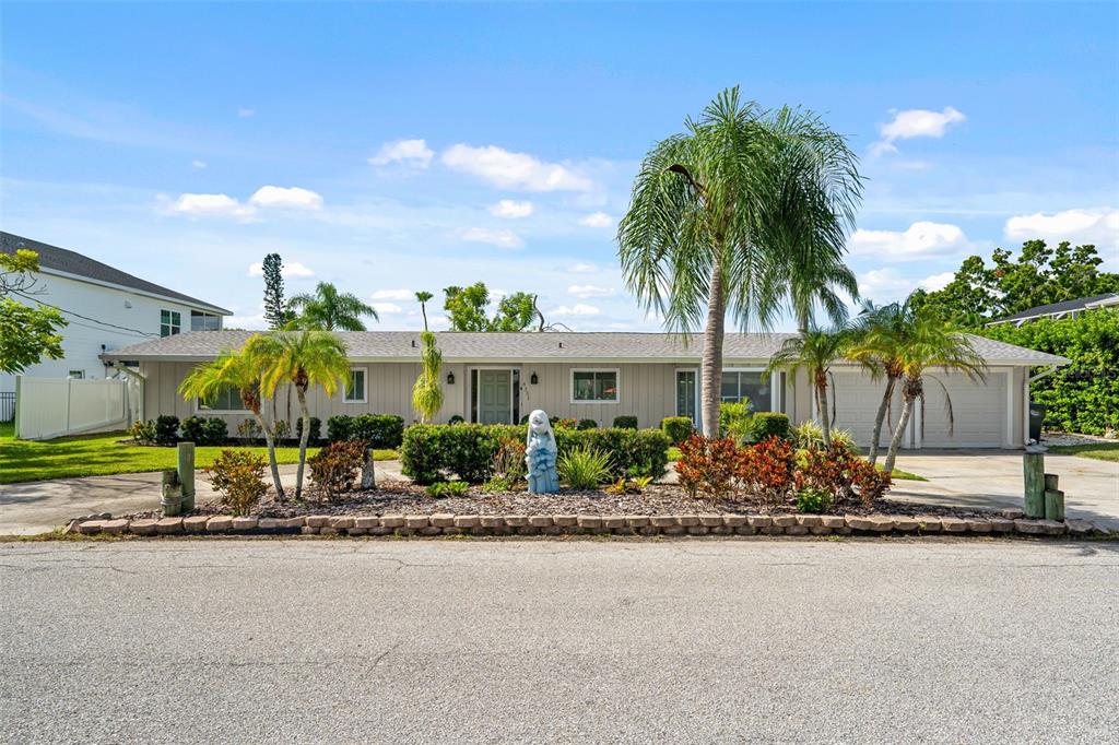 A single-story house with a light-colored exterior, palm trees, and a stone-bordered front garden — 4331 POMPANO LANE, PALMETTO, FL