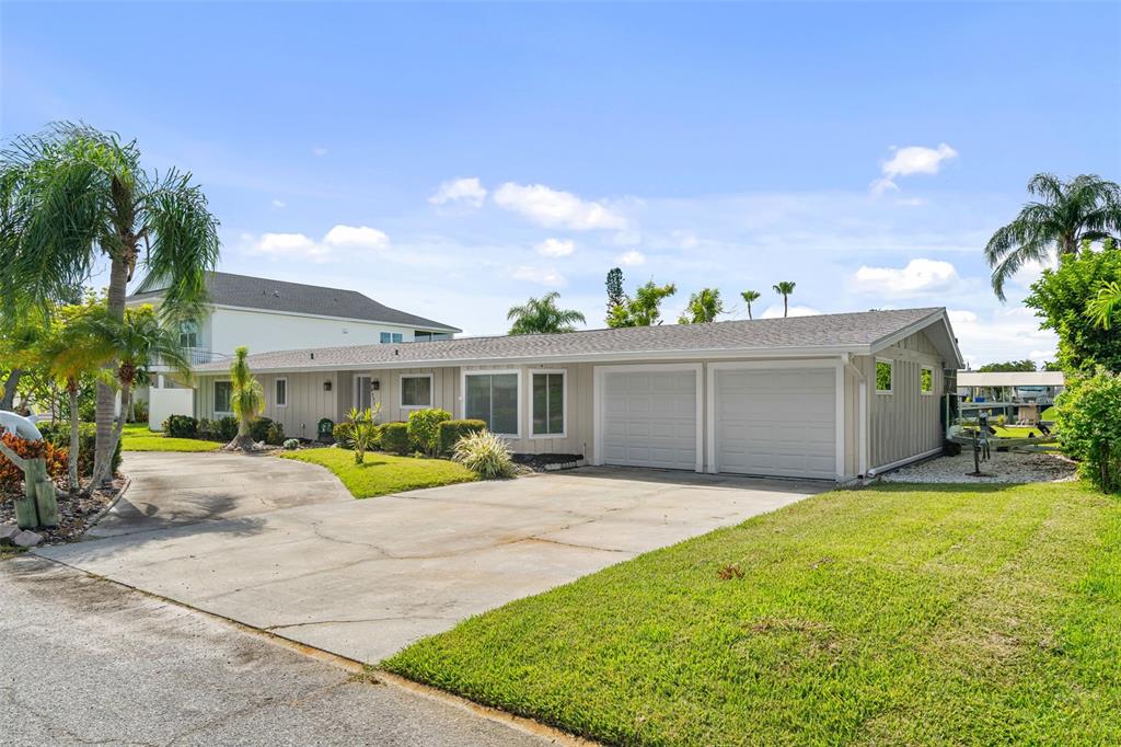 A single-story house with a two-car garage and a concrete driveway under a blue sky — 4331 POMPANO LANE, PALMETTO, FL