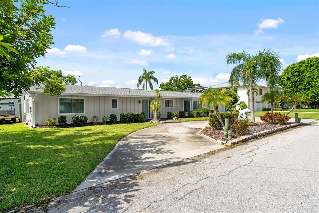 A single-story house with light-colored siding and a concrete driveway sits under a blue sky — 4331 POMPANO LANE, PALMETTO, FL