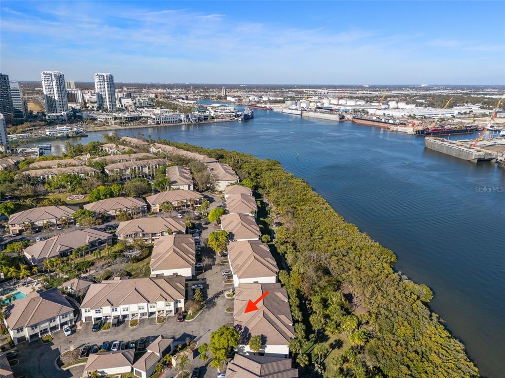 An aerial view shows a residential townhouse complex situated along a waterfront with industrial ships — 1037 NORMANDY TRACE ROAD, TAMPA, FL