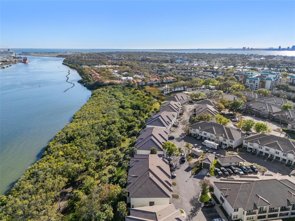 An aerial view shows a waterfront residential complex with townhomes, parking, and dense vegetation — 1037 NORMANDY TRACE ROAD, TAMPA, FL