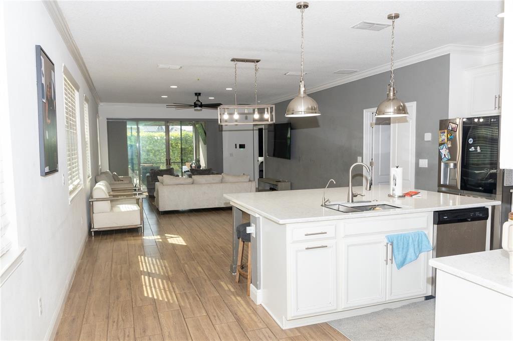 An open-concept kitchen with a white island and pendant lights overlooks a living room area — 6691 ALDER ROAD, HARMONY, FL