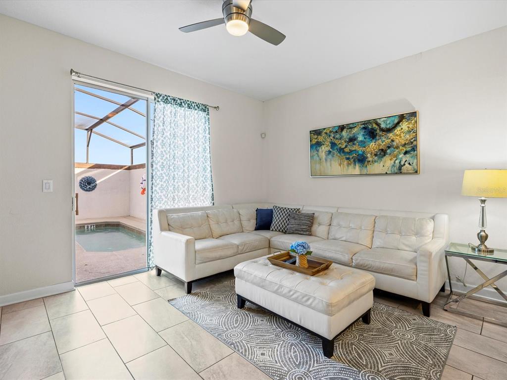 A living room with a white sectional sofa, ottoman, and sliding door opening to a pool — 8991 STINGER DRIVE, DAVENPORT, FL
