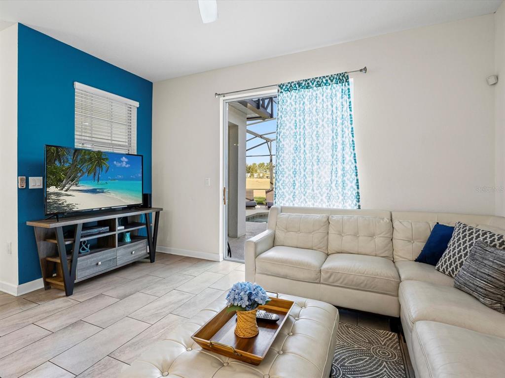 A living room features a blue accent wall, a white sectional sofa, and sliding glass doors — 8991 STINGER DRIVE, DAVENPORT, FL