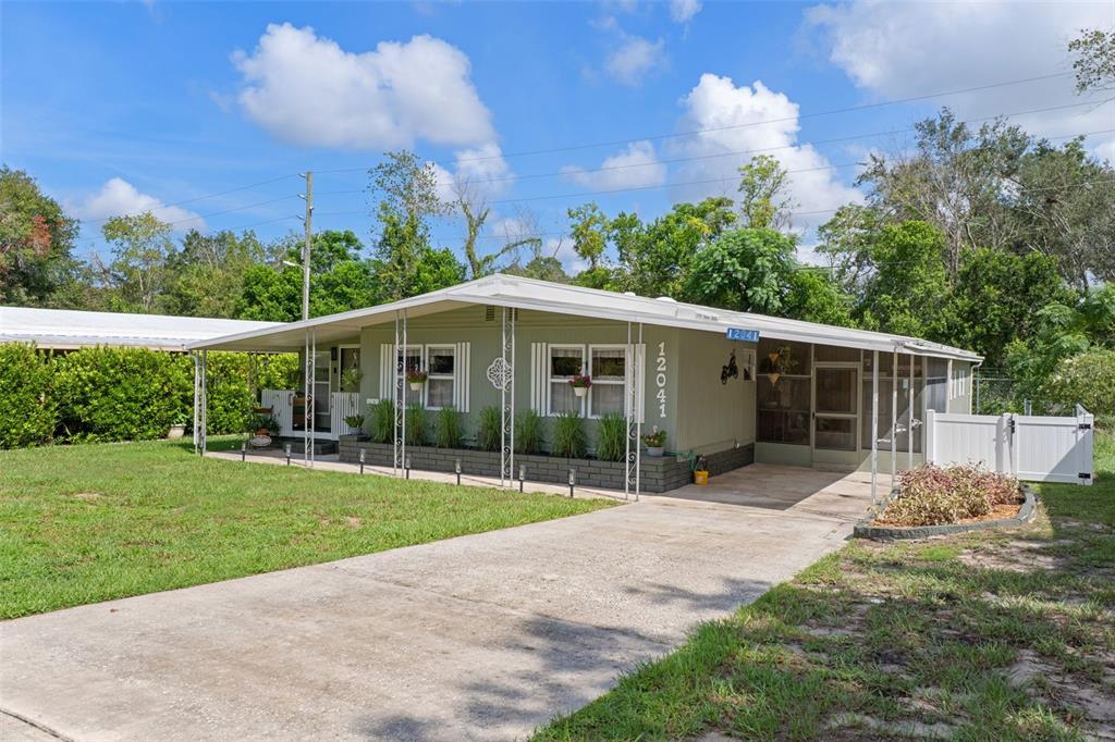 A single-story house with a green exterior, a front porch, and a concrete driveway — 12041 FAIRWAY AVENUE, BROOKSVILLE, FL