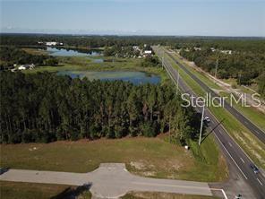 An aerial view shows a vacant lot adjacent to a road and a wooded area — LAKE SMITH ROAD, UMATILLA, FL