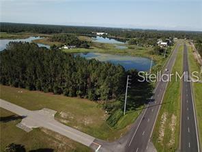 An aerial view shows a vacant lot next to a highway and a small lake — LAKE SMITH ROAD, UMATILLA, FL