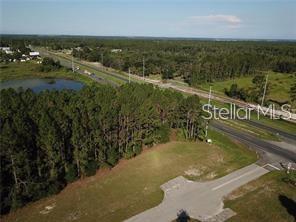 An aerial view shows a vacant, partially wooded lot adjacent to a road and pond — LAKE SMITH ROAD, UMATILLA, FL