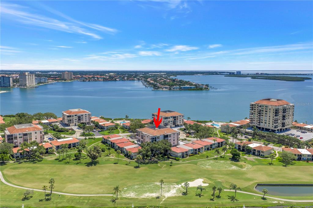 An aerial view shows a multi-story residential building complex situated near a large body of water — 6269 PALMA DEL MAR BOULEVARD S UNIT 508, ST PETERSBURG, FL