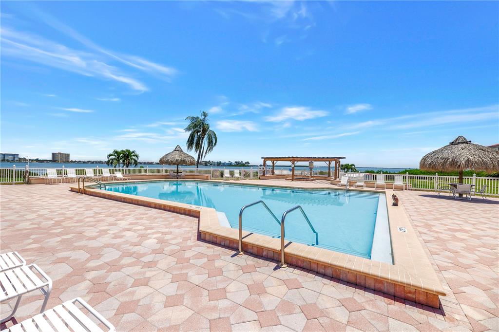 An outdoor swimming pool with a patio, tiki umbrellas, and a view of the water — 6269 PALMA DEL MAR BOULEVARD S UNIT 508, ST PETERSBURG, FL