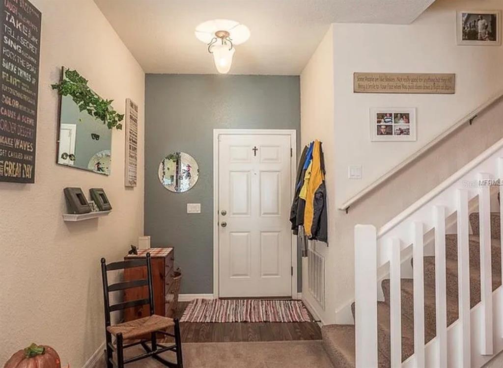 An entryway features a gray accent wall, a white front door, a staircase, and decor — 12316 NE 48TH LOOP, OXFORD, FL