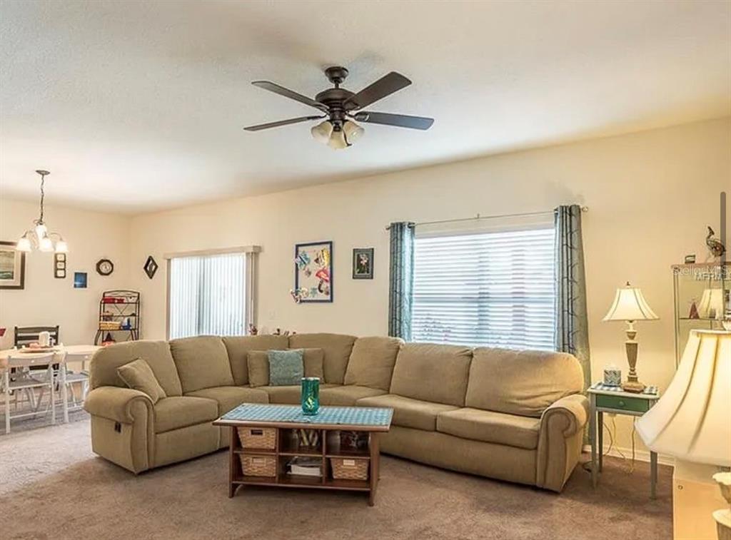 A living room features a large beige sectional sofa, a coffee table, and a ceiling fan — 12316 NE 48TH LOOP, OXFORD, FL