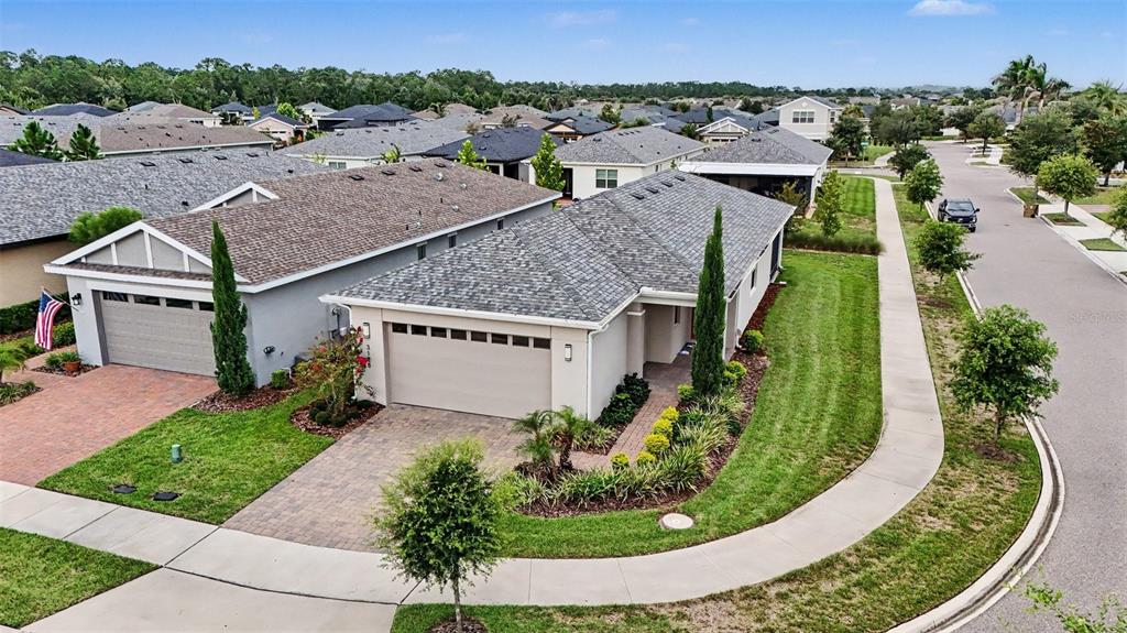 An aerial view of a suburban house with a paved driveway and a corner lot — 3128 SONGBIRD CIR, HARMONY, FL