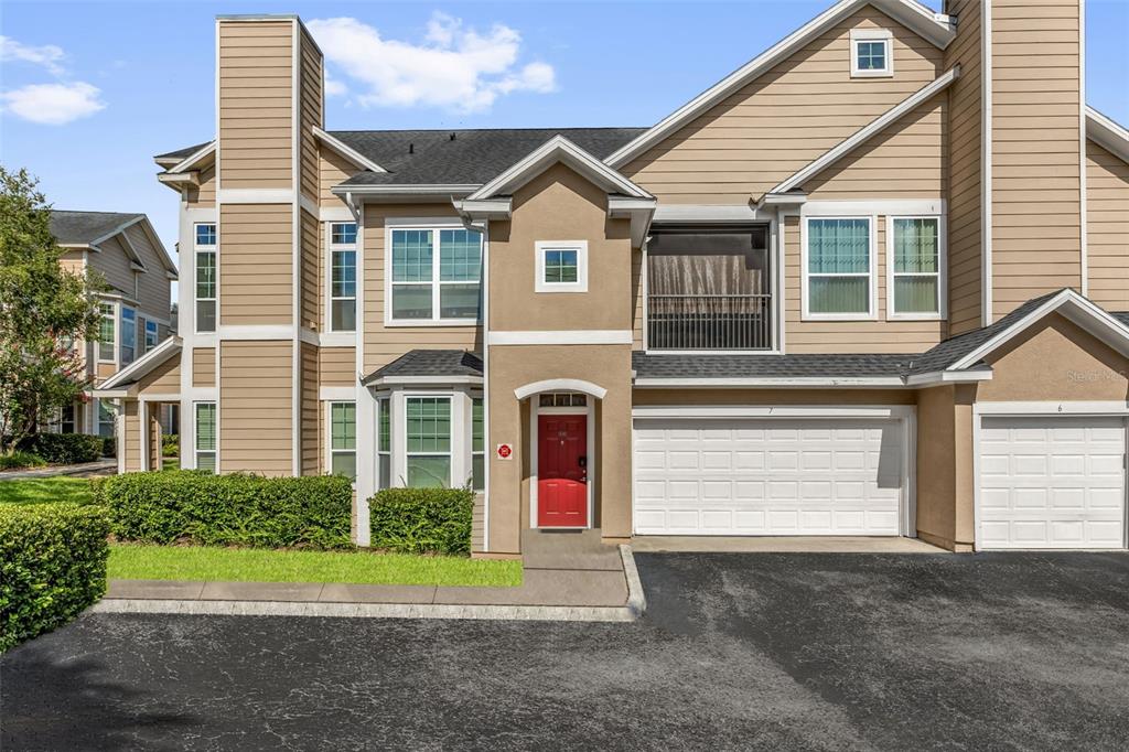 A tan two-story townhouse with a red front door and a white garage door — 1980 ERVING CIRCLE UNIT 111, OCOEE, FL