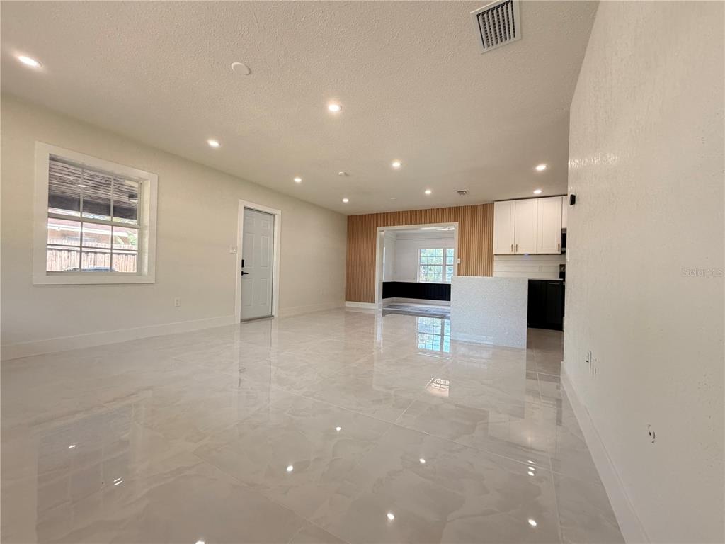 A modern kitchen features white cabinets, a quartz peninsula, stainless steel appliances, and tiled floors — 2405 21ST AVE W, BRADENTON, FL