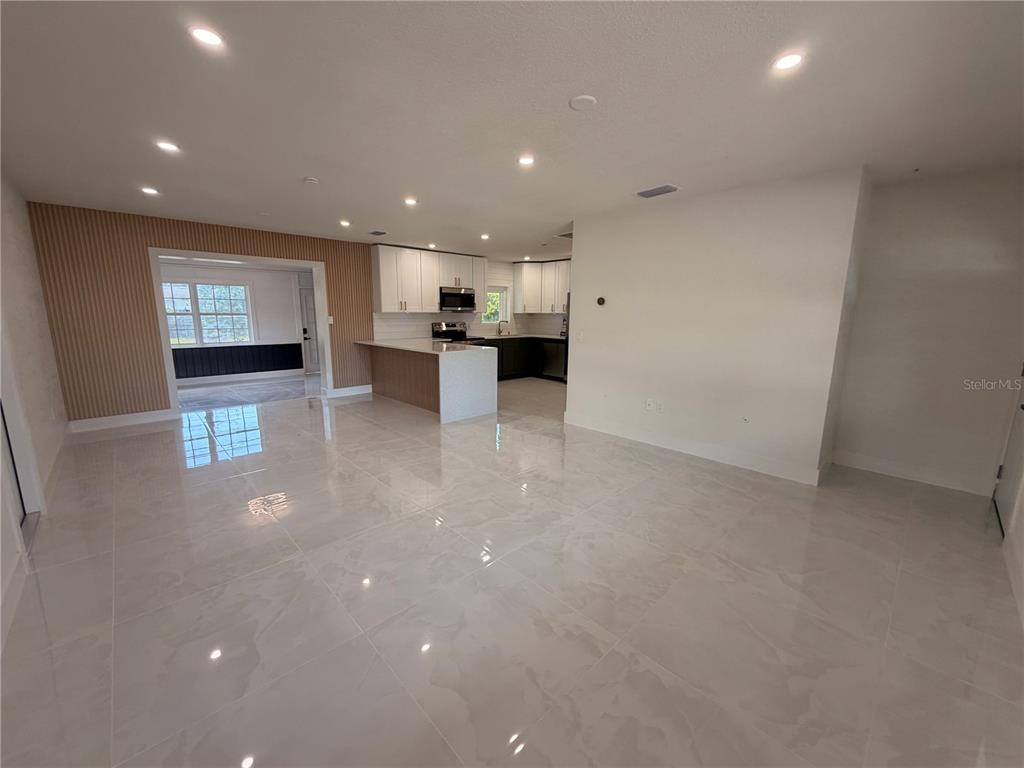 A bright, open-concept living area features polished tile floors, recessed lighting, and a kitchen pass-through — 2405 21ST AVE W, BRADENTON, FL