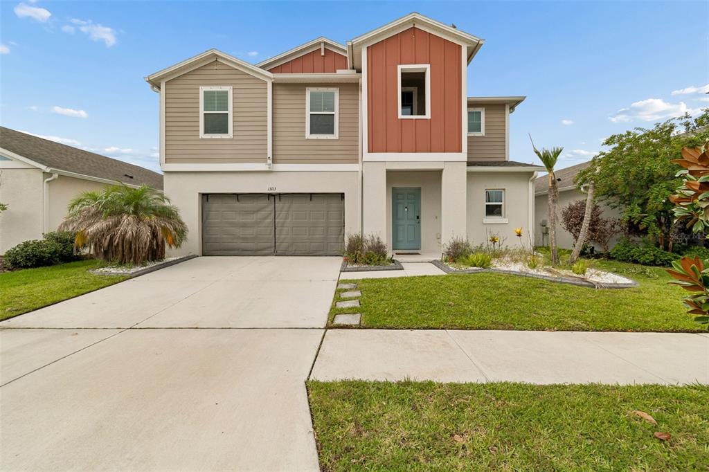 A two-story house with a two-car garage, light-colored siding, and a prominent red-accented entryway — 13113 FRUITVILLE WAY, RIVERVIEW, FL