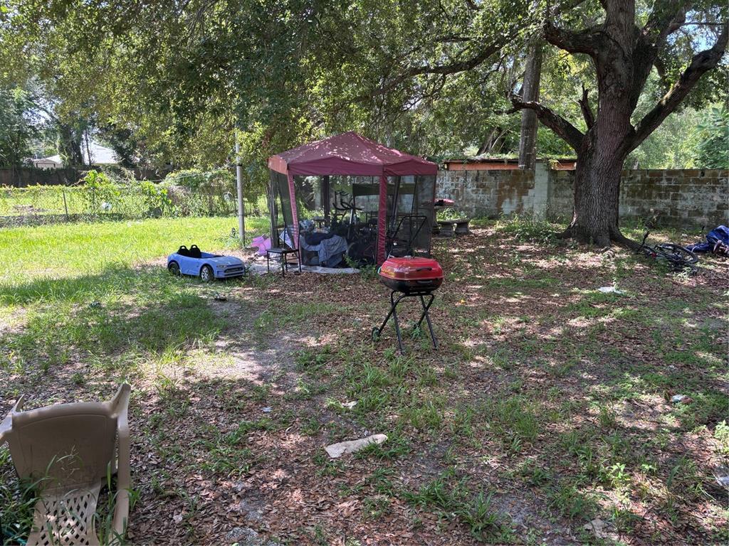 A cluttered living room features a sofa, television, wall art, and various bags and items — 4648 PIEDMONT CT COURT, ORLANDO, FL