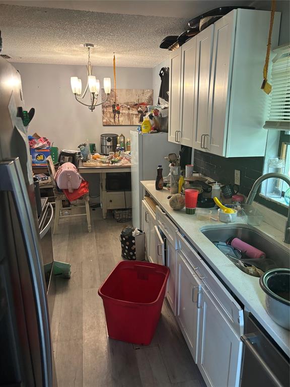 A cluttered kitchen features white cabinets, a stainless steel sink, and a dining area beyond — 4648 PIEDMONT CT COURT, ORLANDO, FL