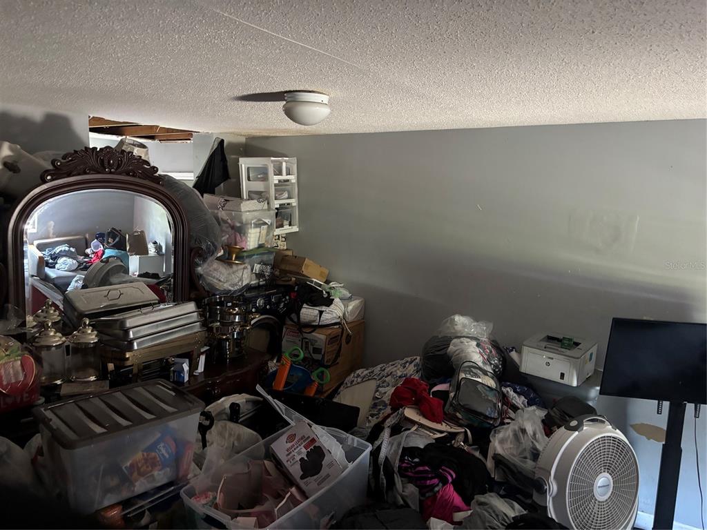 A cluttered room features a large ornate mirror, storage bins, and a floor fan — 4648 PIEDMONT CT COURT, ORLANDO, FL