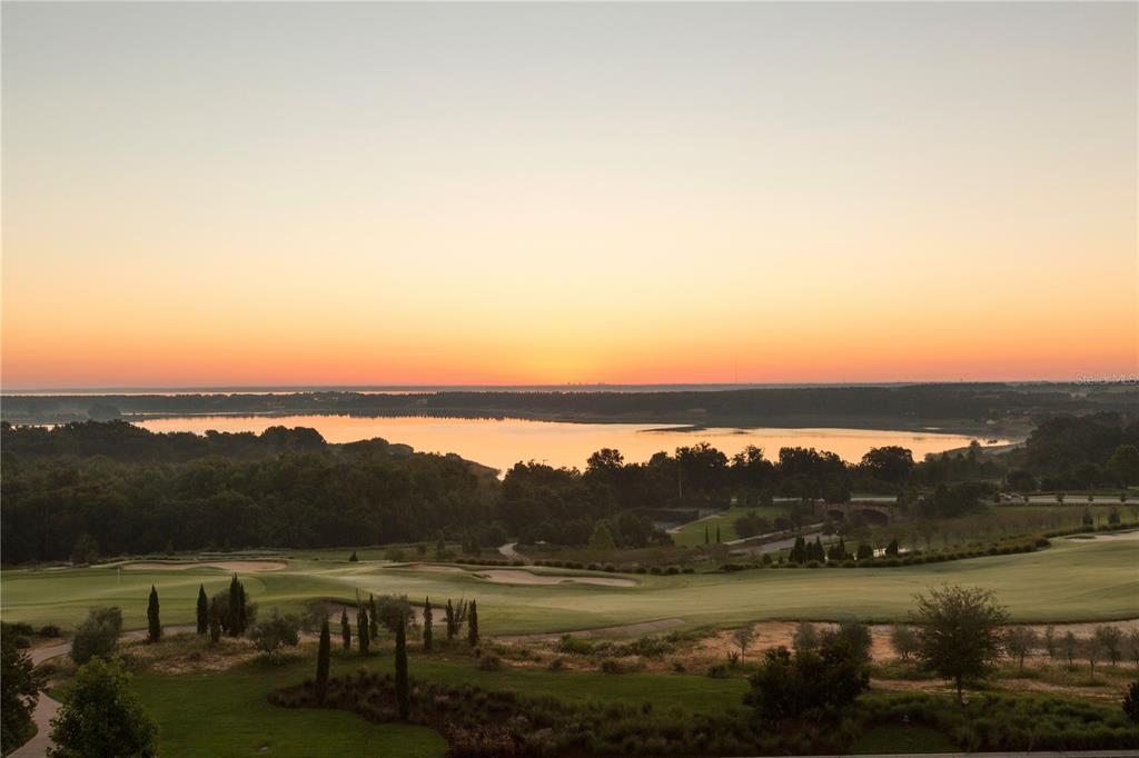 A scenic view of a golf course overlooking a lake at sunset — 16123 PENDIO DRIVE, BELLA COLLINA, FL
