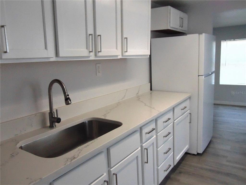 A kitchen features white cabinets, a stainless steel sink, and white marble-patterned countertops — 4214 E PALIFOX STREET, TAMPA, FL