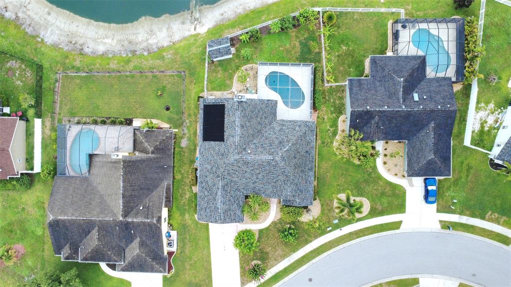 An aerial view shows three suburban houses with swimming pools and backyards near a pond — 6734 60TH STREET CIRCLE E, PALMETTO, FL