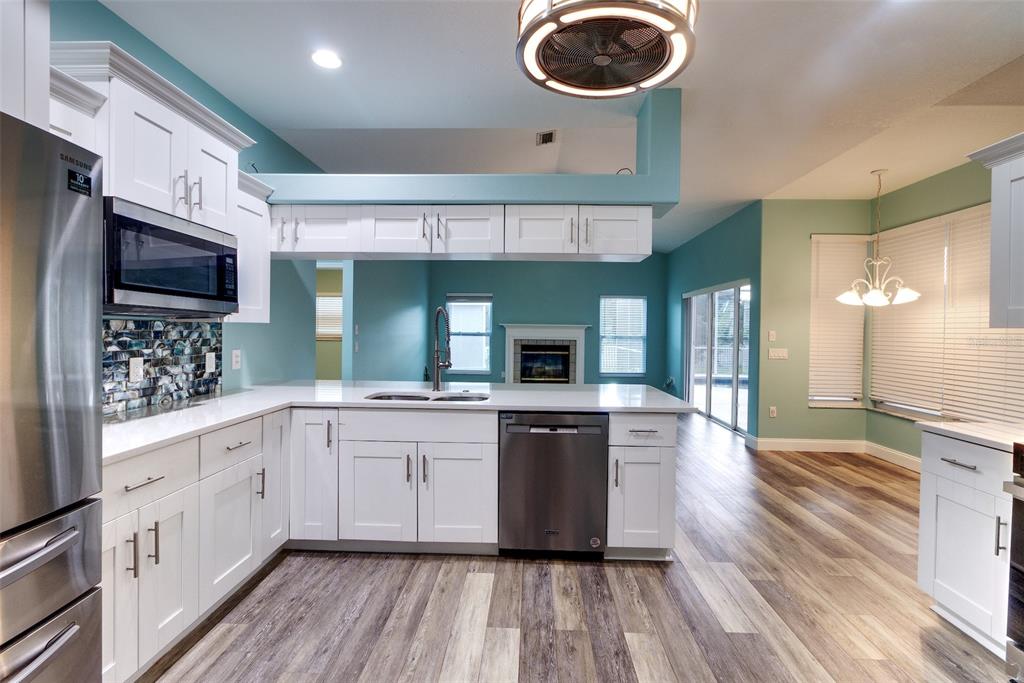 A kitchen with white cabinets, stainless steel appliances, and teal walls overlooks a dining area — 6734 60TH STREET CIRCLE E, PALMETTO, FL