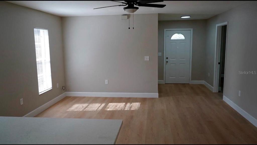 An open living area features light wood-look flooring, a ceiling fan, and a front door — 4514 CYPRESS STREET, ORLANDO, FL