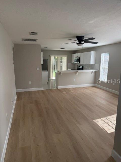 An open-concept living area features light wood-look flooring, a ceiling fan, and a kitchen breakfast bar — 4514 CYPRESS STREET, ORLANDO, FL