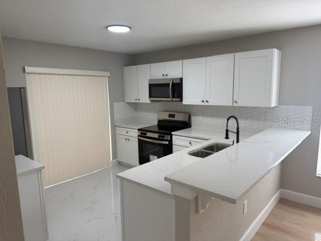 A kitchen features white cabinets, quartz countertops, stainless steel appliances, and light-colored tile flooring — 4514 CYPRESS STREET, ORLANDO, FL